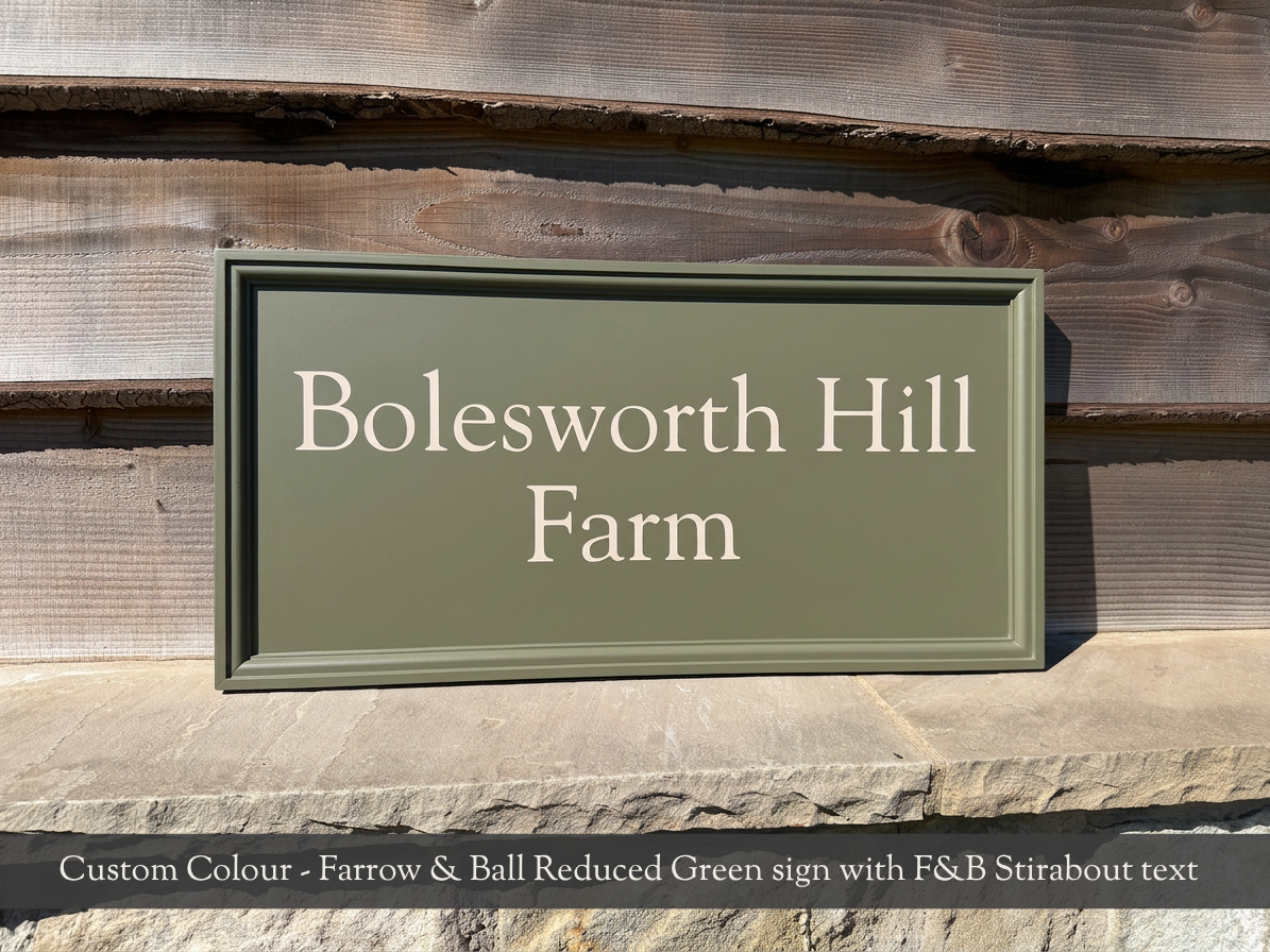 A rectangular custom-finished sign for 'Bolesworth Hill Farm' in reduced green, mounted on a rustic wooden wall. A text banner at the bottom reads 'Custom Colour - Farrow & Ball Reduced Green sign with F&B Stirabout text'.